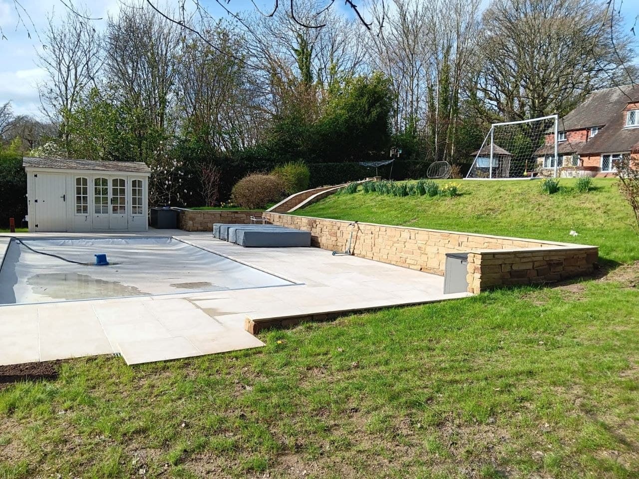 Swimming pool framed by a sandstone terrace and natural stone retaining wall