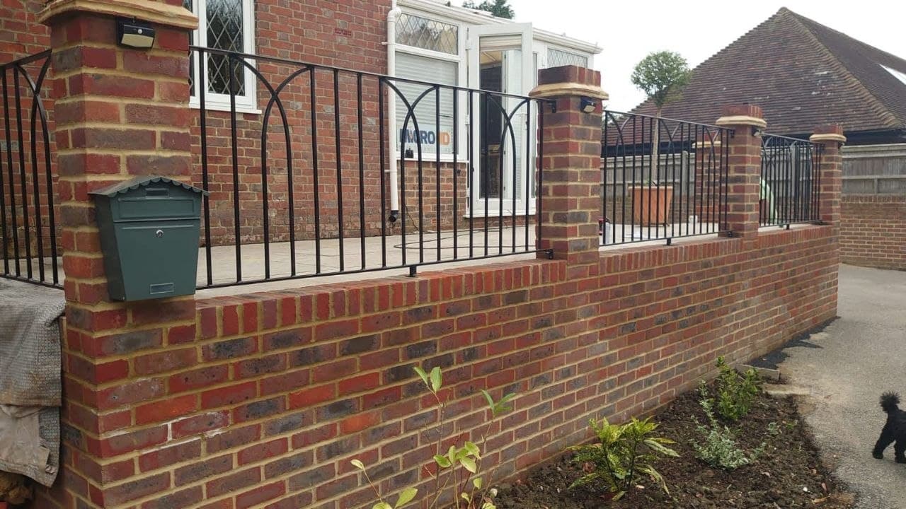 Red-brick boundary wall with piers, wrought-iron railings and a post box